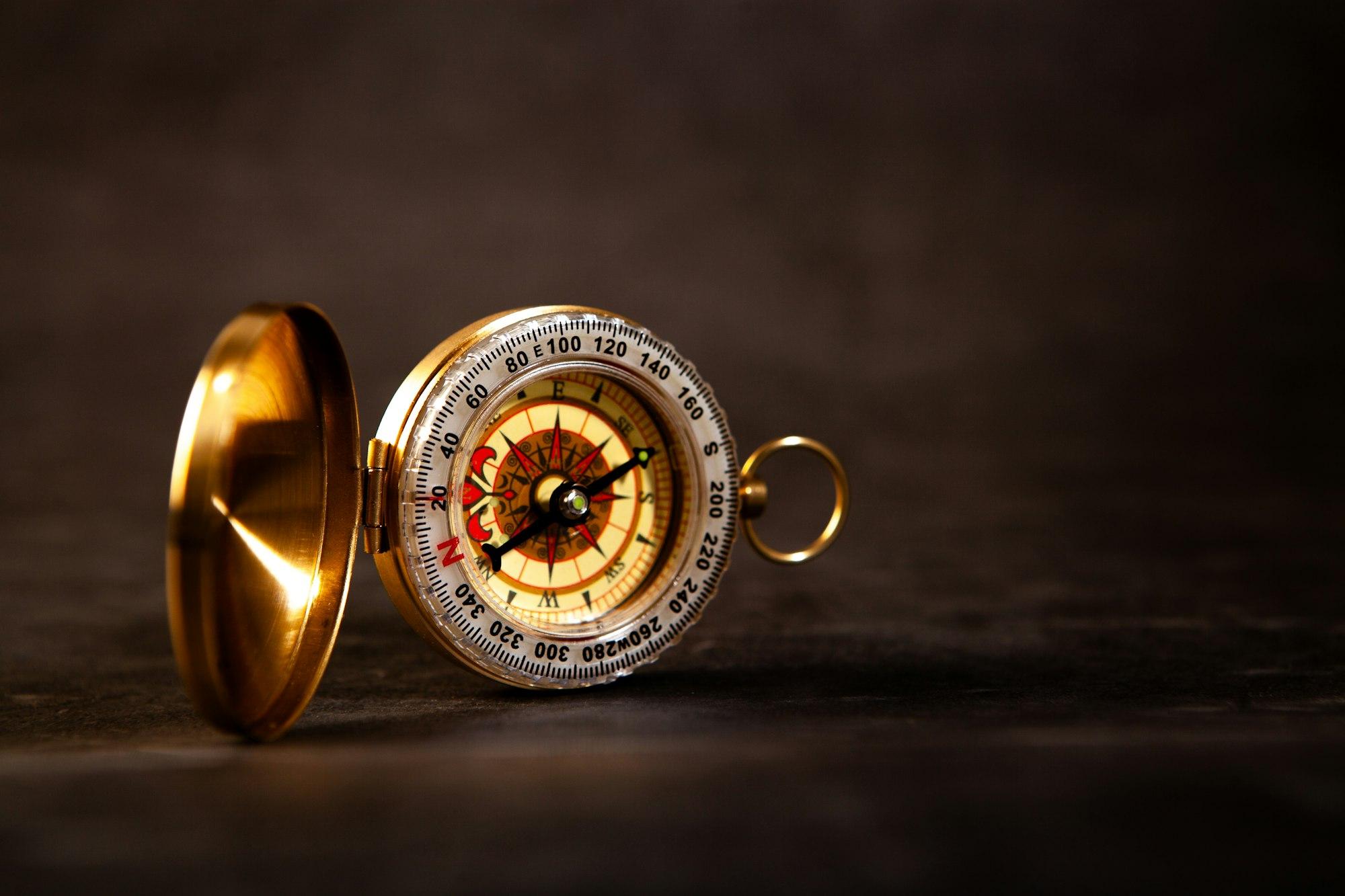 A brass compass resting on a wooden surface